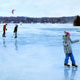 Painting of skaters with hockey sticks on frozen lake in the Laurentians.